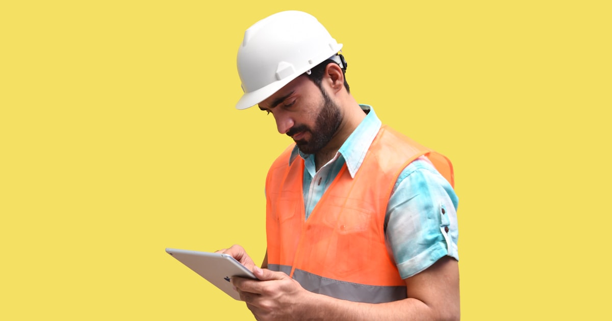 Field service worker in safety vest reviewing a checklist on a tablet